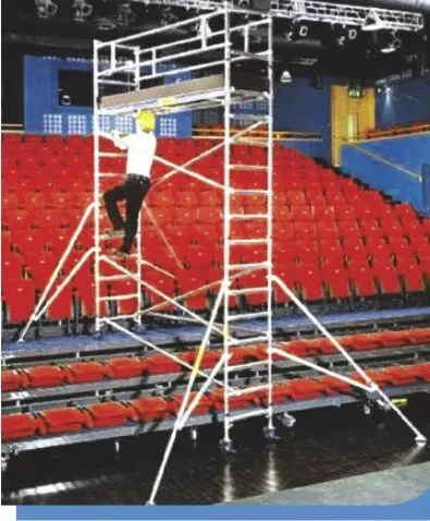 Aluminum scaffold tower set up in a theater auditorium with red seats under a lighting truss