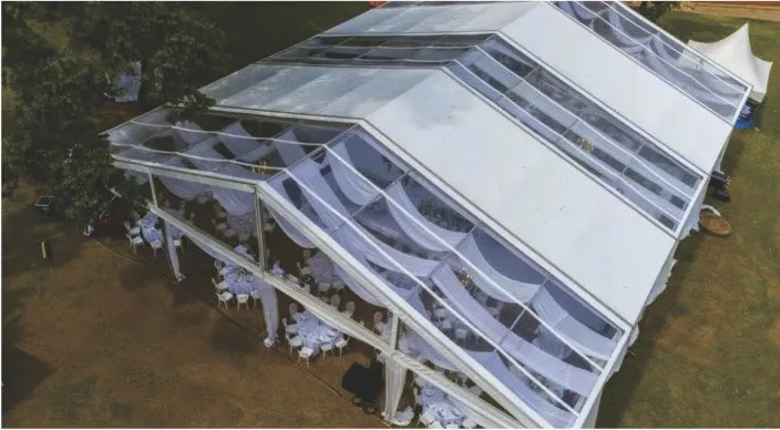 Aerial view of a curved-roof event tent with translucent roof panels and draped interior